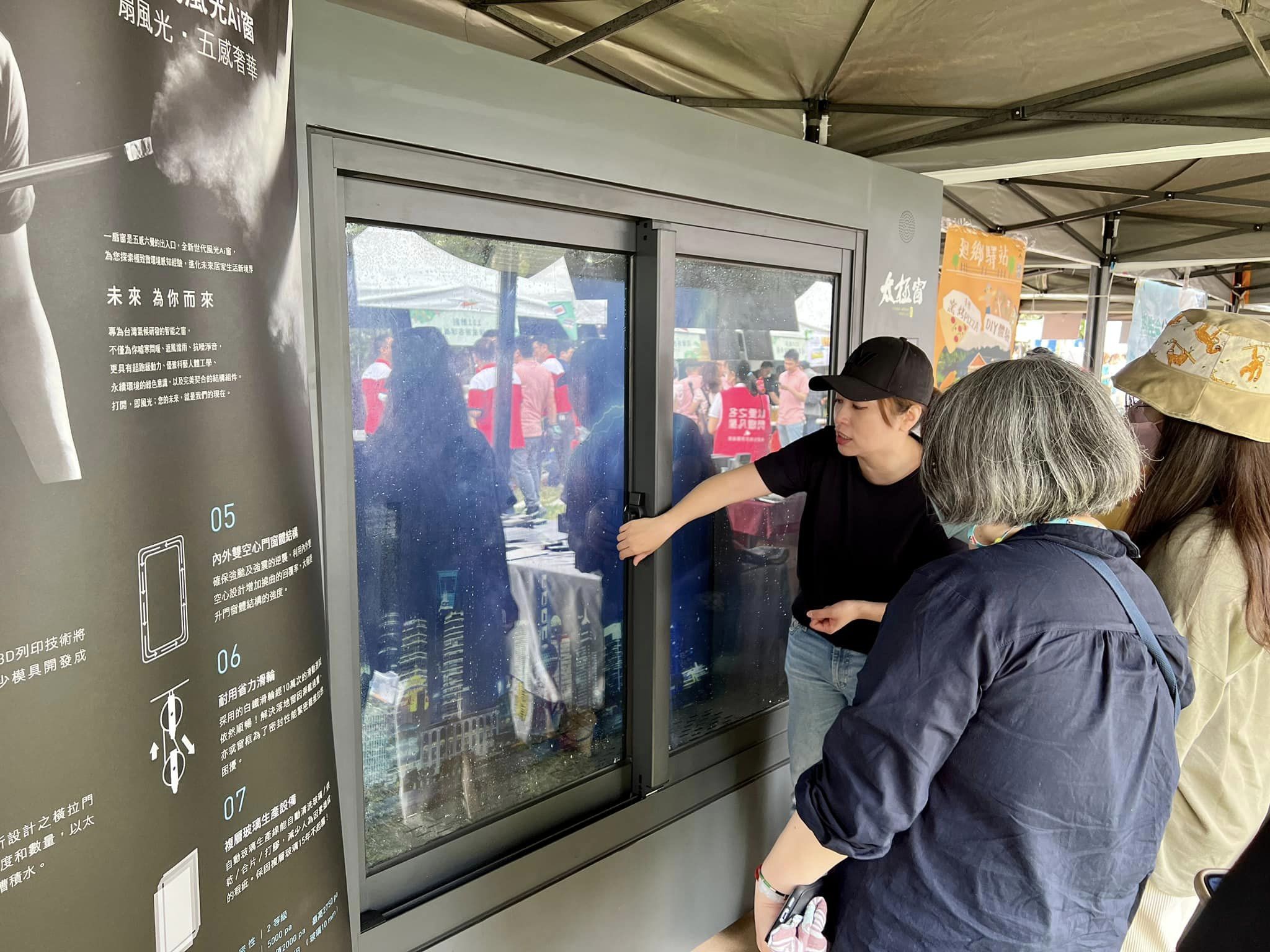 夏綠地奇幻樂園活動:工作人員向參觀民眾示範風光Ai窗橫拉窗的實際開關,旁側看板列出內外雙空心門窗體結構、耐用省力滑輪與複層玻璃生產設備等特色