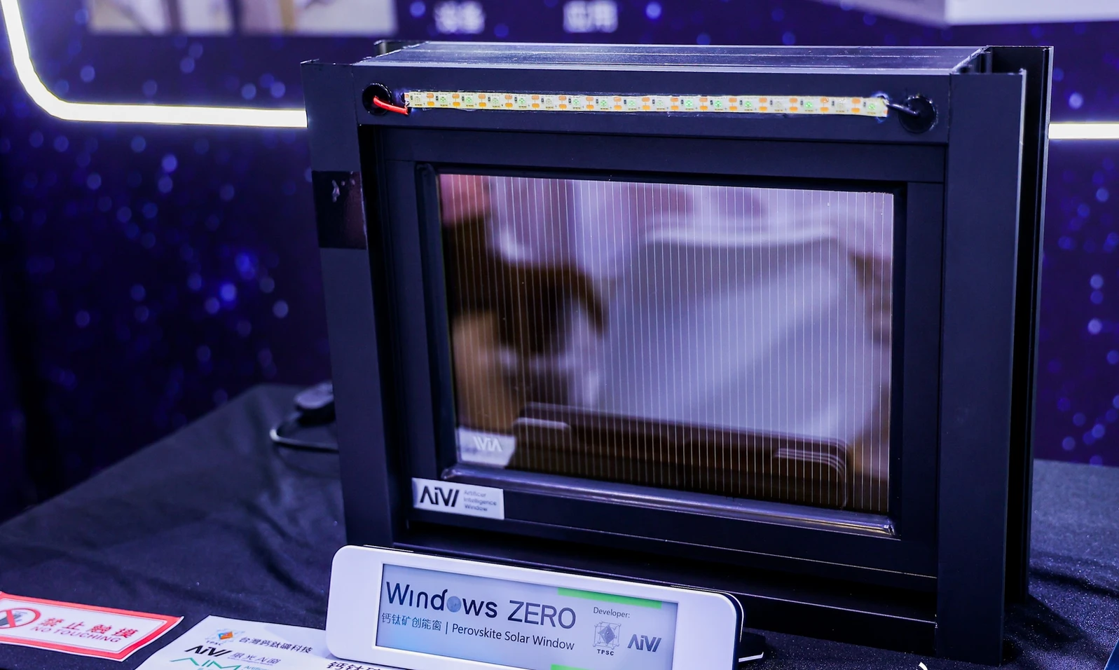 Windows ZERO 鈣鈦礦創能窗（Perovskite Solar Window）實品：黑色鋁框窗嵌入鈣鈦礦發電玻璃，上方 LED 燈條由該窗自身發電點亮，由台灣鈣鈦礦科技 TPSC 與風光Ai窗共同開發