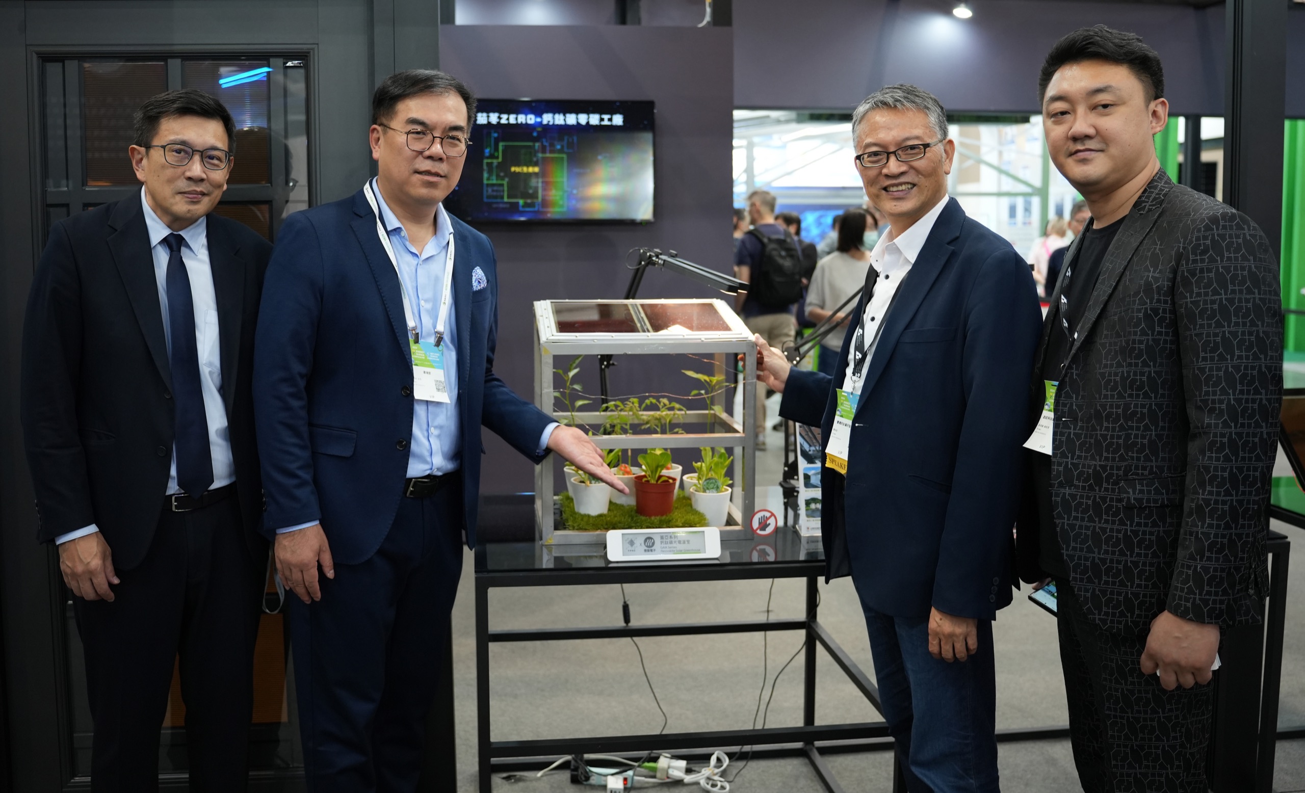 台灣國際智慧能源週合影：與會代表於「鈣苺ZERO 鈣鈦礦零碳工廠」展示區，展台為鈣鈦礦薄片電源室植栽溫室模型