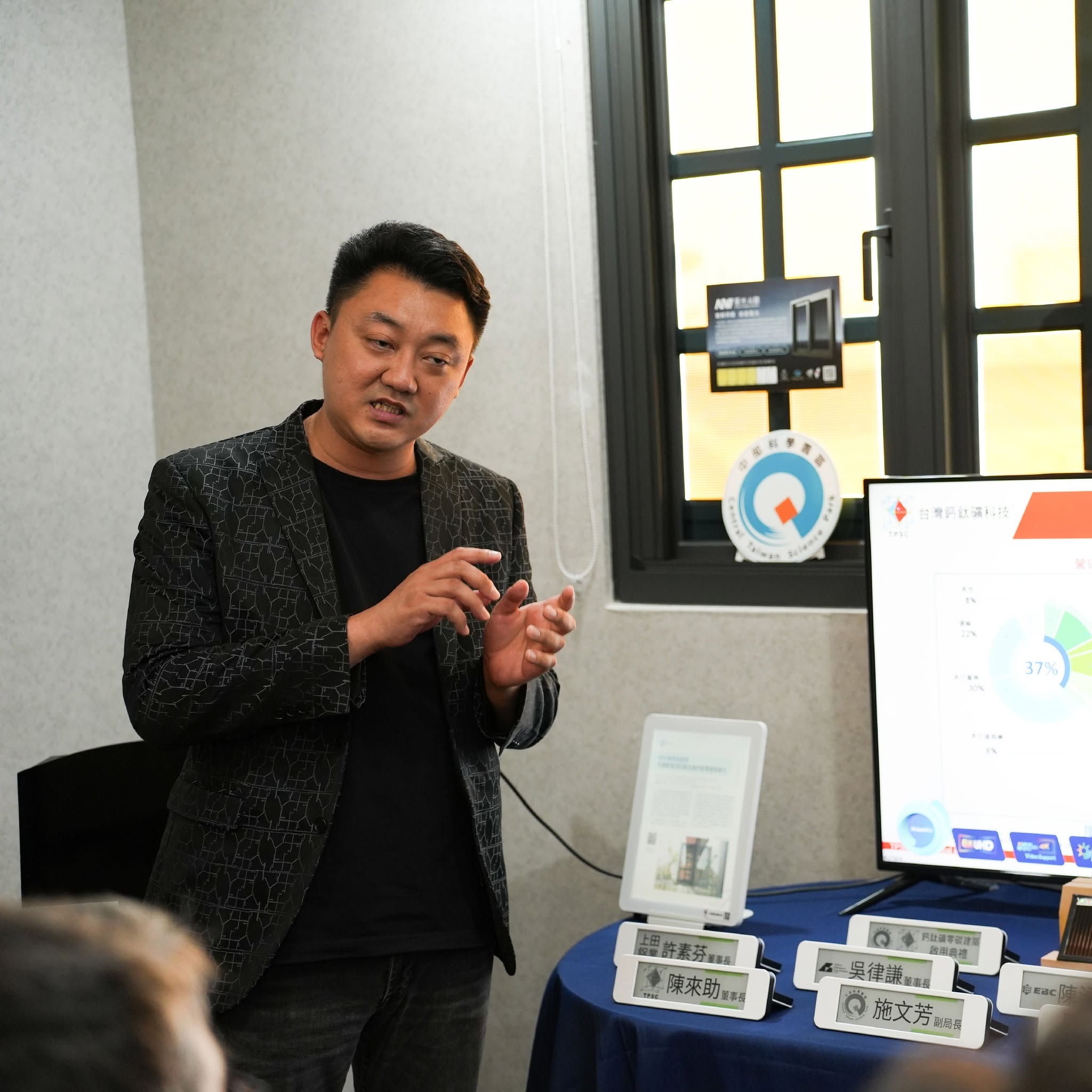 中科鈣鈦礦零碳建築啟用典禮:風光集團代表於中部科學園區標誌前簡報台灣鈣鈦礦科技技術,桌上為與會貴賓席次牌